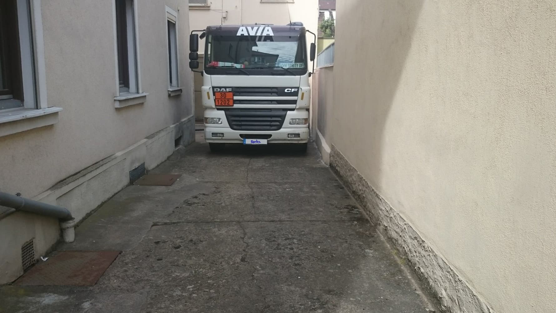 Tankwagen in einer Hofeinfahrt, die kaum breiter ist als er selbst